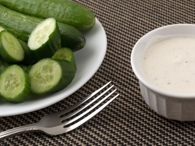 fresh cucumber slices and ranch dip on a table
