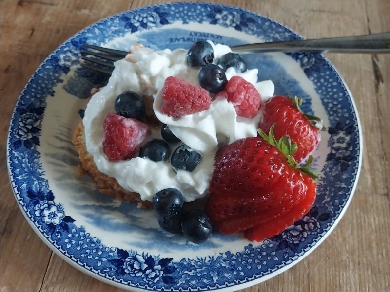 fresh berry and whipped cream dessert on a vintage china plate