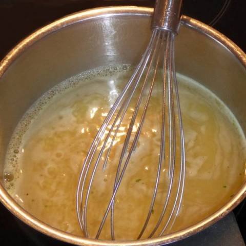 Bone Broth simmering in a copper kettle with a copper wire whisk