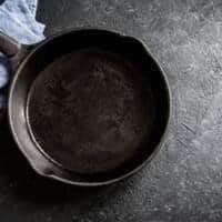 Cast iron skillet with seasoned surface for cooking and maintenance.
