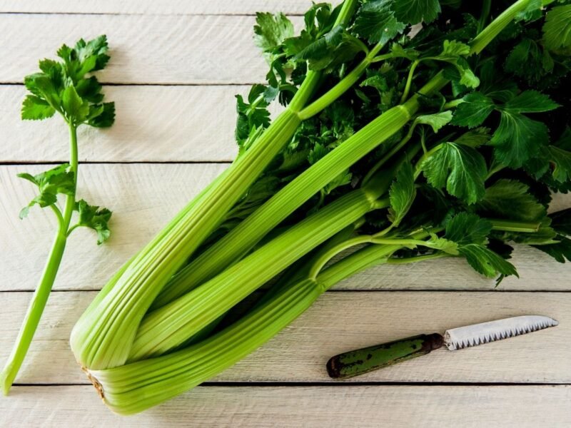 fresh bunch of celery on a wooden cutting board
