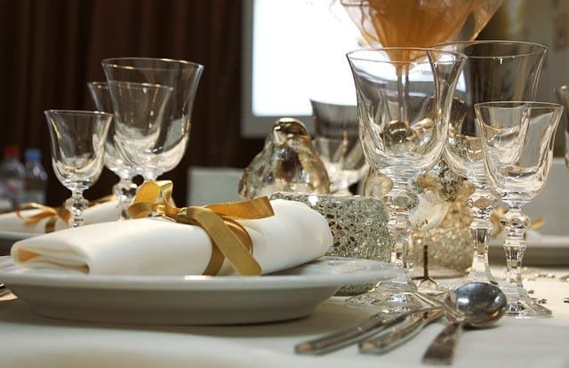 Christmas table setting with wine glasses and golden ribbon on white napkin