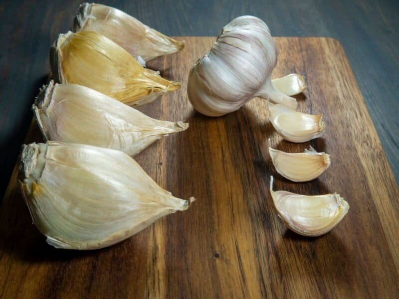 Fresh garlic bulbs and cloves on wooden cutting board.