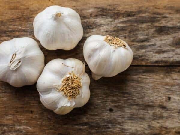 four fresh garlic bulbs on a wooden table