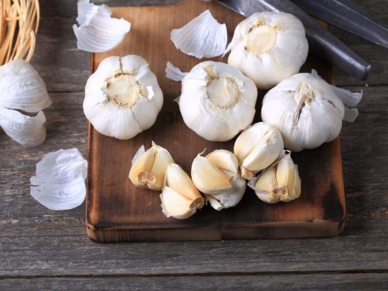 fresh garlic cloves and bulbs on a cutting board