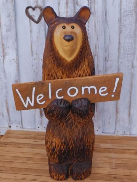 a 3 foot tall hand carved wooden bear holding a welcome sign