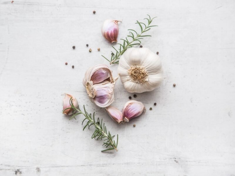 fresh garlic with peppercorns and rosemary on a table
