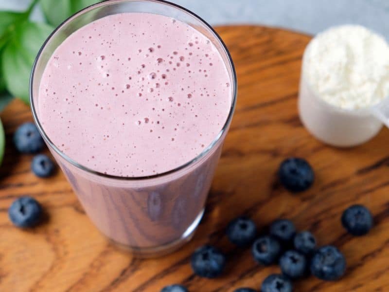 beautiful fresh homemade protein powder power shake in a glass with fresh blueberries