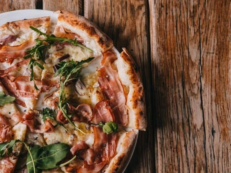 Freshly baked homemade pizza with crispy crust, cheese, and toppings on a rustic wooden table.