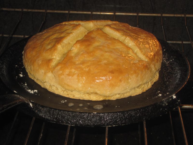 golden brown loaf of flat bread on a cast iron skillet
