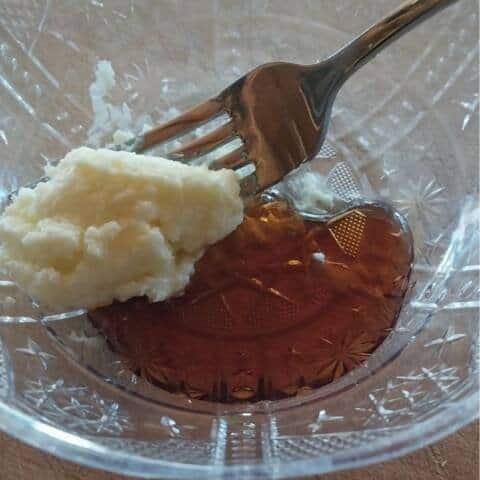Maple syrup and butter mixture in glass bowl with fork.