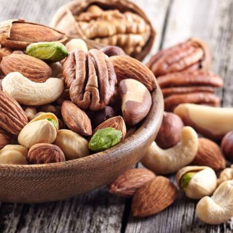 a wooden bowl full of a variety of nuts and seeds