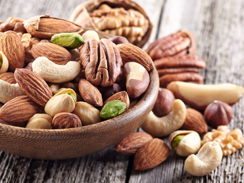 a wooden bowl full of a variety of nuts and seeds