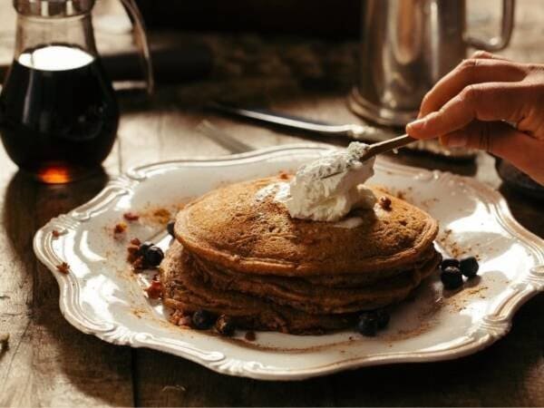 Delicious stack of homemade pancakes topped with whipped cream and berries for a hearty breakfast.