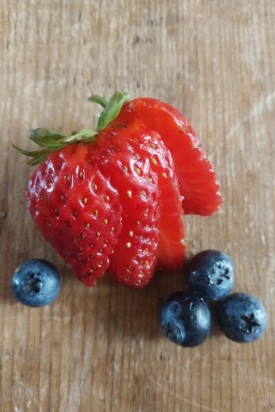 sliced strawberry with 44 blueberries on a wooden table