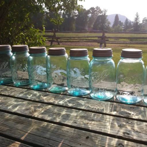 blue canning jars lined up in a row on the homesteader's front porch