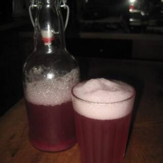 Raspberry Water Kefir in a Glass with a Swing Cap Bottle on the Side