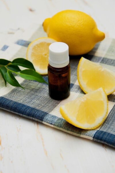brown bottle of lemon essential oil with fresh lemons 